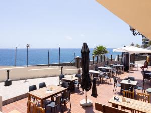 een restaurant met tafels en parasols en de oceaan bij Live Balcon del Mar in Costa Del Silencio