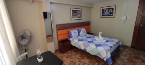 a small bedroom with a bed and a fan at Aruba Suite Hotel in Lima