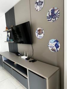 einen Tisch mit einem TV und Platten an der Wand in der Unterkunft Alto Padrão Tenório 2suites com ar, wifi e piscina in Ubatuba