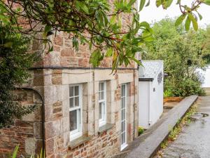 una antigua casa de ladrillo con ventanas blancas y entrada en Little Polgray en St Austell