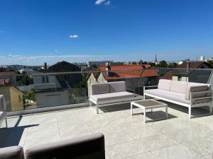 un patio con 2 sofás y una mesa en el techo en Grand Appartement de standing Rooftop Jacuzzi, en Malakoff