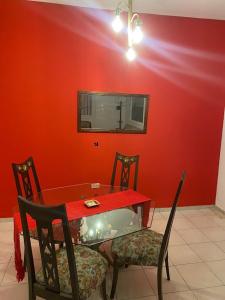 einen Tisch mit zwei Stühlen und einer roten Wand in der Unterkunft DEPARTAMENTO VINTAGE 2 HABITACIONES 2 BAÑOS LiVING COMEDOR COCINA A 2 CUADRAS PEATONAL CENTRO SAN JUAN in San Juan