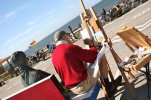 a man is painting a statue on the beach at Hotel Duinlust in Domburg