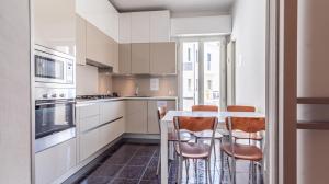 a white kitchen with a table and chairs in it at Grand Central - Affitti Brevi Italia in Modena