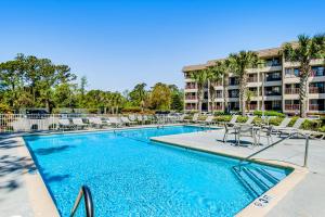 a swimming pool with chairs and a building at HH Beach & Tennis 322B in Hilton Head Island