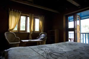 RudraprayāgにあるShivanandi River Lodgeのベッドルーム1室(ベッド1台、椅子2脚、窓付)