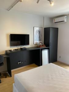 um quarto com uma cama e uma secretária com uma televisão em Garvey Park Hotel em Brasília