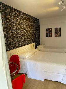 a bedroom with two beds and a red chair at Garvey Park Hotel in Brasilia