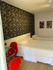 um quarto de hotel com duas camas e uma cadeira vermelha em Garvey Park Hotel em Brasília
