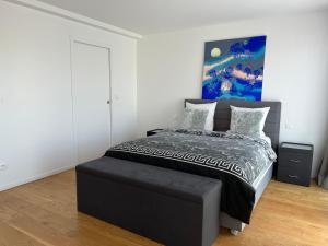 Un dormitorio con una cama negra con una pintura azul en la pared en Grand Appartement de standing Rooftop Jacuzzi, en Malakoff