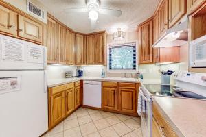 uma cozinha com armários de madeira e um frigorífico branco em High Hammock 171 em Seabrook Island