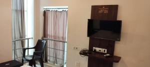 a room with a television and a chair and a window at The Royal Comforts in Visakhapatnam