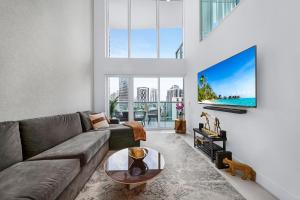 a living room with a couch and a tv at Sunbeam Plush 2 Story Loft in Miami