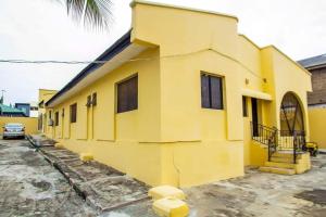 un edificio amarillo con un coche aparcado delante de él en ARO (1.0) 2BD Studio Flat (Abule-Egba/Lagos), en Agege