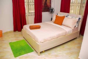 a bed in a room with red curtains and a green rug at ARO (1.0) 2BD Studio Flat (Abule-Egba/Lagos) in Agege