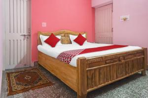 Schlafzimmer mit einem Holzbett mit roten Kissen in der Unterkunft OYO Flagship Hotel Kashyap Heritage in Patna