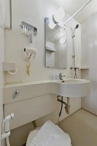 a white bathroom with a sink and a mirror at Zodiak Paskal by KAGUM Hotels in Bandung