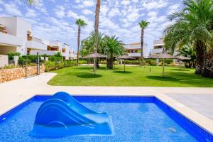 een blauwe glijbaan in een zwembad met palmbomen bij Secreto De La Zenia ID200 in Playa Flamenca