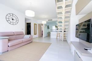 uma sala de estar com um sofá rosa e uma televisão em Secreto De La Zenia ID200 em Playa Flamenca