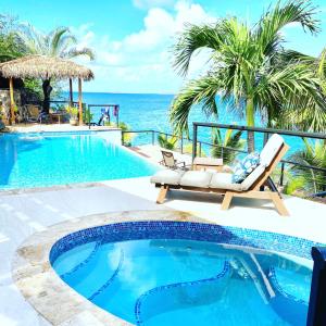 a pool with two chairs and the ocean in the background at Lime in de Coconut Villa in Cruz Bay