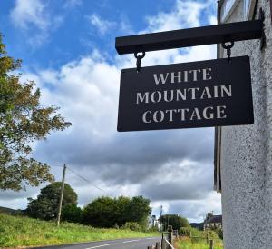 um sinal para um chalé de montanha branco na beira de uma estrada em White Mountain Cottage em Newry