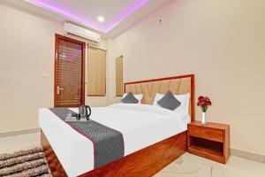 een slaapkamer met een groot wit bed en een tafel bij Townhouse Kalyanpur Metro in Kaliānpur
