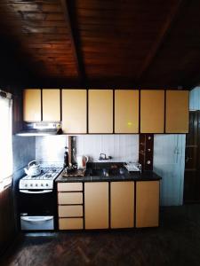 a kitchen with a stove and a sink and cabinets at Cumbre House in Malargüe