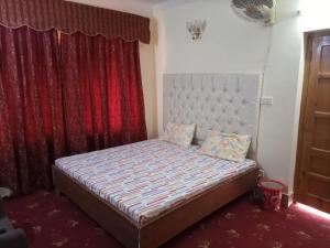 a small bed in a room with a red curtain at Galaxy apartments in Lower Topa