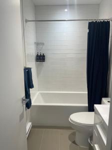 La salle de bains est pourvue d'une baignoire blanche et de toilettes. dans l'établissement Hochelag Nook, à Montréal