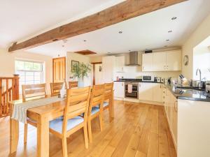 a kitchen and dining room with a wooden table and chairs at Old Rectory Cottages in Aberhafesp