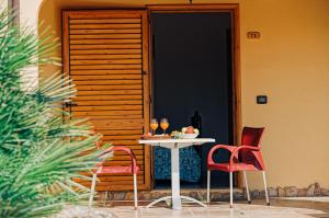 einen Tisch und zwei Stühle vor einer Tür in der Unterkunft Agriturismo Rocce Bianche - Porticato in Arbus