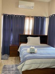 a bedroom with a large bed with blue curtains at Cozy Studio with free parking on premises. in Grand Anse