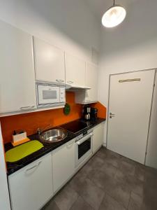 eine kleine Küche mit einer Spüle und einer Mikrowelle in der Unterkunft Vienna Apartment Gutarra II in Wien