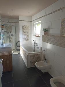 a bathroom with a tub and a toilet and a sink at Apartmán Rose in Ostopovice