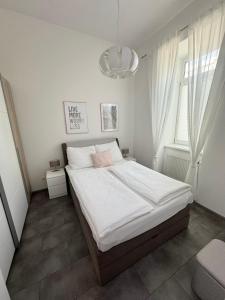 a bedroom with a bed with white sheets and a chandelier at Vienna Apartment Gutarra II in Vienna
