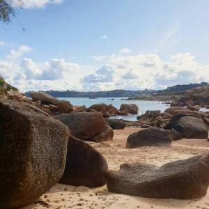 a beach with rocks and a body of water at Grand appartement renové centre historique proche plages in Perros-Guirec