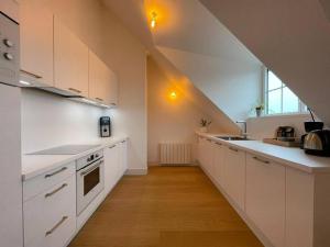 an attic kitchen with white cabinets and a staircase at Grand appartement renové centre historique proche plages in Perros-Guirec