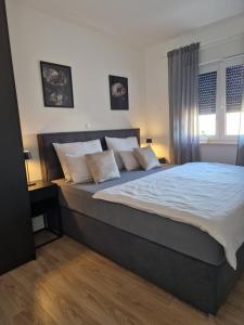 um quarto com uma cama grande com lençóis brancos e almofadas em Deluxe Apartment Mila em Nin