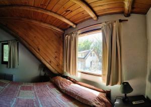 Cama en habitación con ventana grande en Cabañas Budapest en Capilla del Monte