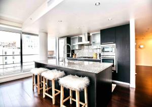 a kitchen with a large counter with stools in it at Victoria's best location 2 bedroom luxe condo in Victoria