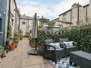 a patio with chairs and an umbrella and some plants at The Bay Cottage - Morecambe Bay in Morecambe