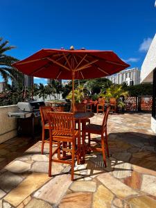 Luana Waikiki Park Views في هونولولو: طاولة وكراسي تحت مظلة على الفناء