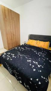 Una cama con una manta negra con flores blancas. en KLIA Homestay Apartment - 2 room, en Sepang