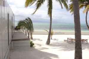 a beach with palm trees and a building and the ocean at The Zanzibar Beach House-West in Pingwe