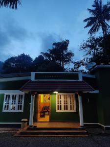 a green house with a front porch at night at Lovely Home Stay Munnar in Munnar