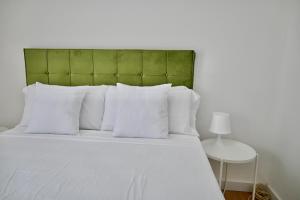 a white bed with a green headboard and white pillows at For You Rentals Coqueto y Cómodo apartamento en Entrevías JOR64D in Madrid