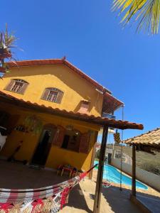 una casa amarilla con una línea de ropa junto a una piscina en Casa Lazer&Tranquilidade @lazer.tranquilidade en Brumadinho