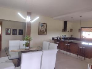 ein Wohnzimmer mit weißen Stühlen und eine Küche in der Unterkunft Família Coelho Hospedagem in Igaratá