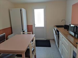 a kitchen with a table and a refrigerator at Maison avec jacuzzi proche plages in Avrillé