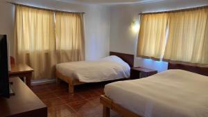 a hotel room with two beds and a television at Hospedaje la Florentina in Pica